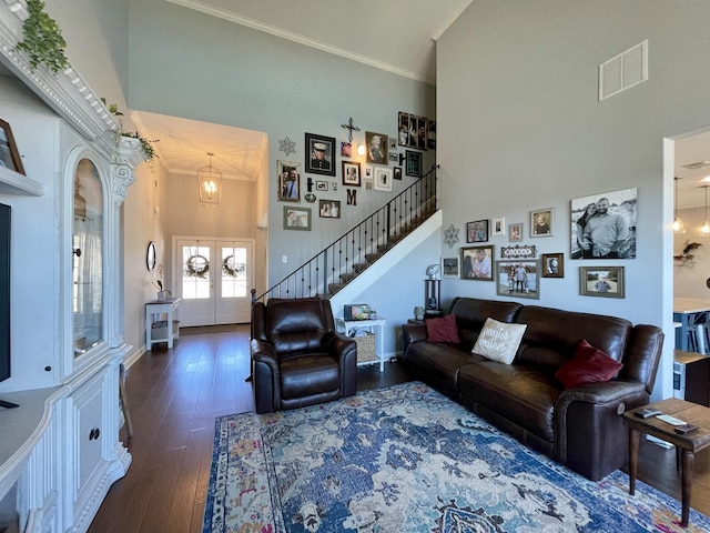 living room featuring dark hardwood / wood-style flooring, a towering ceiling, ornamental molding, and french doors