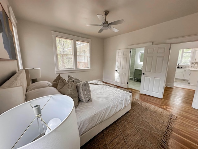 bedroom with ceiling fan, ensuite bath, dark wood-type flooring, and sink