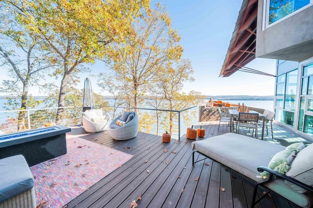 wooden terrace with a water view and an outdoor living space with a fire pit