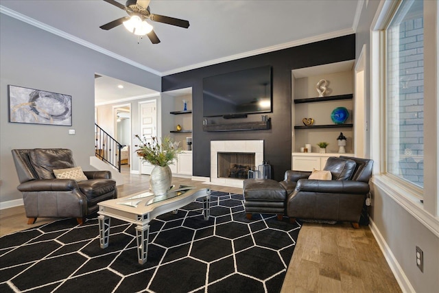 living room with ornamental molding, light wood-type flooring, and built in features