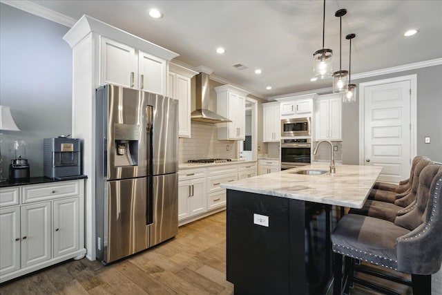 kitchen featuring sink, white cabinetry, pendant lighting, wall chimney range hood, and stainless steel appliances