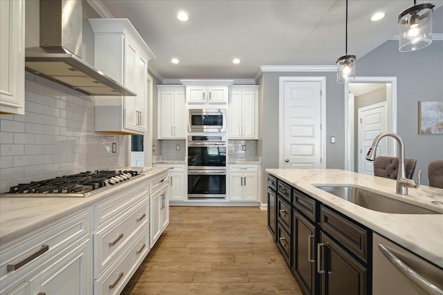 kitchen with white cabinetry, appliances with stainless steel finishes, wall chimney range hood, and pendant lighting