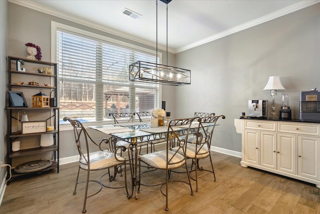 dining area featuring light wood-type flooring, crown molding, and a notable chandelier