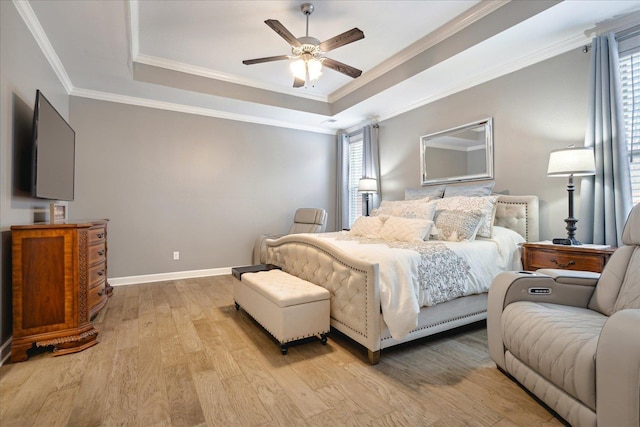 bedroom with a tray ceiling, light hardwood / wood-style floors, and multiple windows