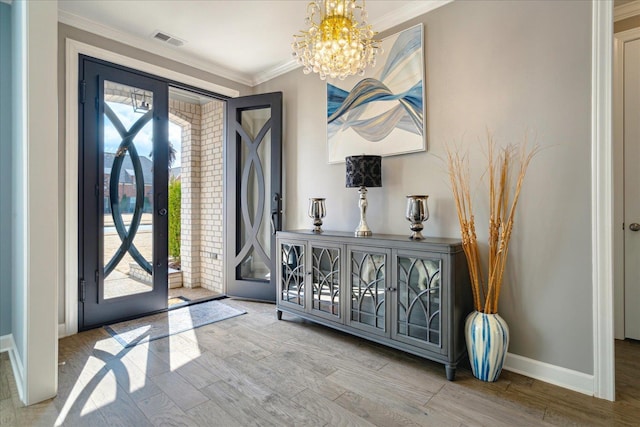 foyer entrance with hardwood / wood-style flooring, a healthy amount of sunlight, crown molding, and an inviting chandelier