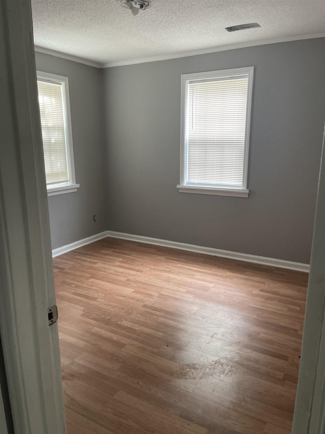 unfurnished room featuring a healthy amount of sunlight, wood-type flooring, and ornamental molding