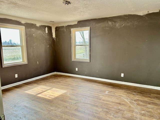 spare room featuring wood-type flooring and a textured ceiling