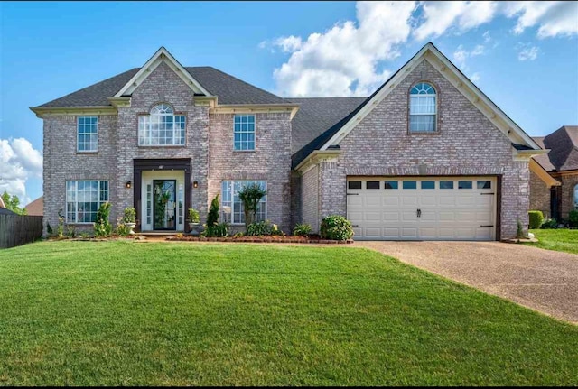 view of front of house with a front yard, concrete driveway, brick siding, and fence