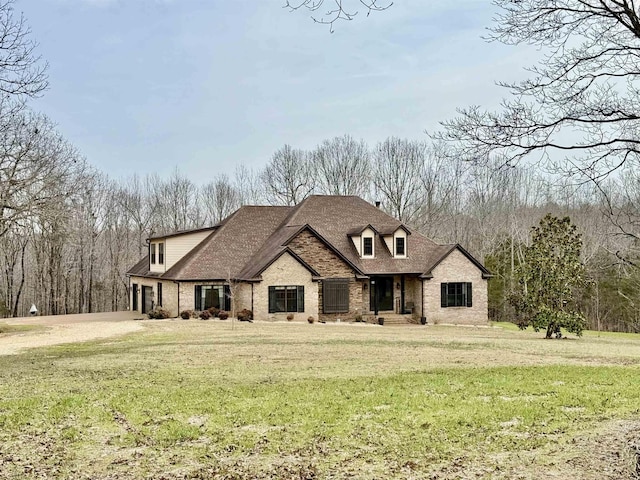 french country style house featuring brick siding, a front yard, and a shingled roof