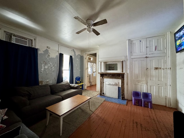 unfurnished living room with hardwood / wood-style floors, ceiling fan, a wall mounted AC, and a brick fireplace