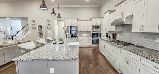 kitchen with a center island with sink, light stone counters, pendant lighting, a kitchen breakfast bar, and stainless steel appliances