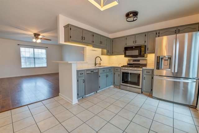 kitchen with gray cabinetry, stainless steel appliances, sink, backsplash, and light tile patterned floors