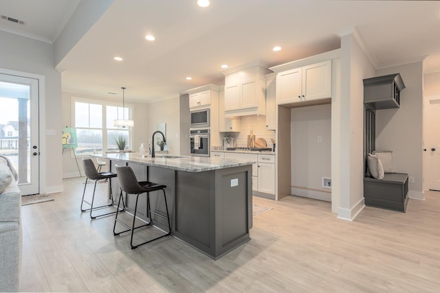 kitchen with white cabinets, an island with sink, appliances with stainless steel finishes, and sink