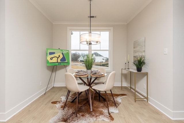 dining space featuring light wood-type flooring, a chandelier, and crown molding