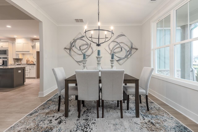 dining space featuring a chandelier, crown molding, and light hardwood / wood-style flooring