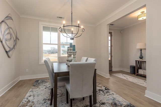 dining room featuring hardwood / wood-style floors, crown molding, and a chandelier