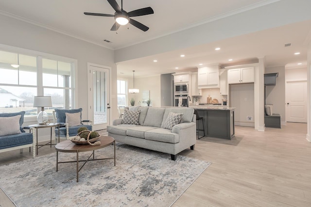 living room featuring ceiling fan, light hardwood / wood-style floors, and crown molding