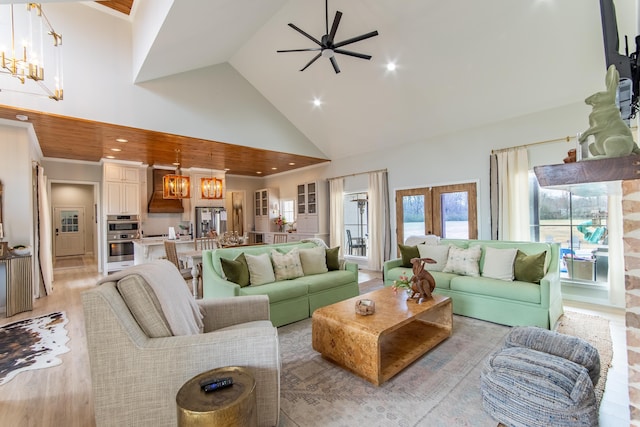 living room featuring ceiling fan with notable chandelier, french doors, high vaulted ceiling, and light hardwood / wood-style flooring