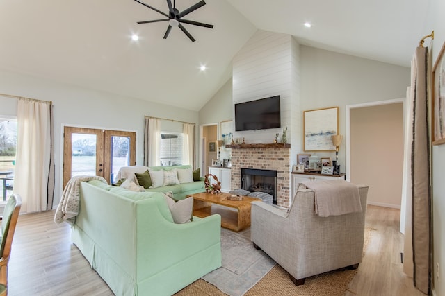 living room with a brick fireplace, a healthy amount of sunlight, french doors, and light hardwood / wood-style floors