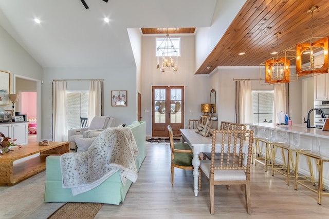 dining area with light hardwood / wood-style flooring, high vaulted ceiling, french doors, and a notable chandelier