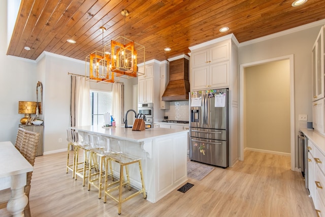 kitchen featuring an island with sink, stainless steel appliances, a breakfast bar, custom exhaust hood, and pendant lighting