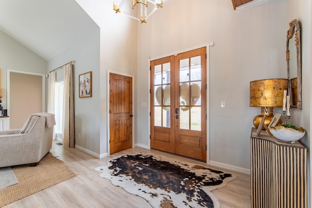 entryway with light hardwood / wood-style flooring, a chandelier, french doors, and high vaulted ceiling