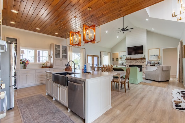 kitchen featuring appliances with stainless steel finishes, hanging light fixtures, sink, white cabinetry, and a kitchen island with sink