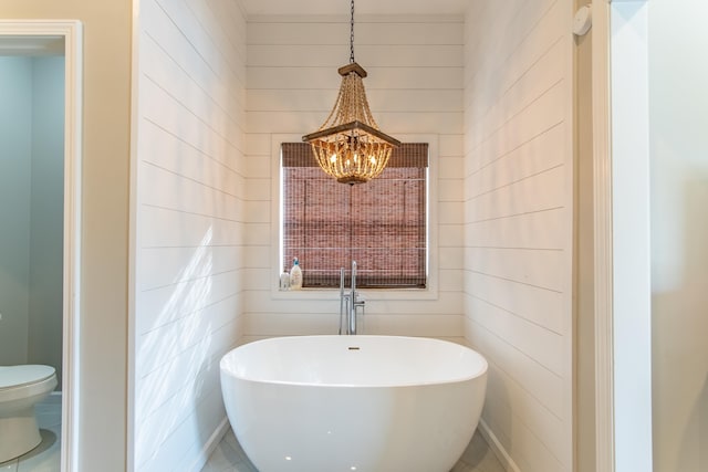 bathroom with a notable chandelier, toilet, and a tub to relax in