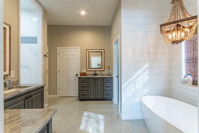 bathroom featuring a notable chandelier, vanity, a tub, and tile patterned floors