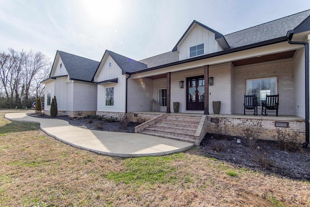 view of front of home featuring covered porch, a front yard, and french doors