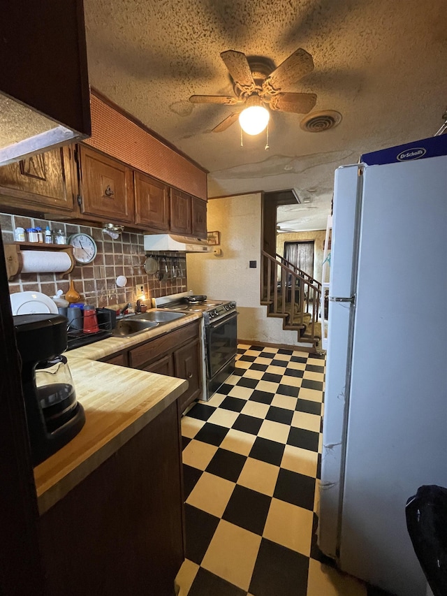 kitchen featuring backsplash, black electric range, a textured ceiling, white refrigerator, and ceiling fan