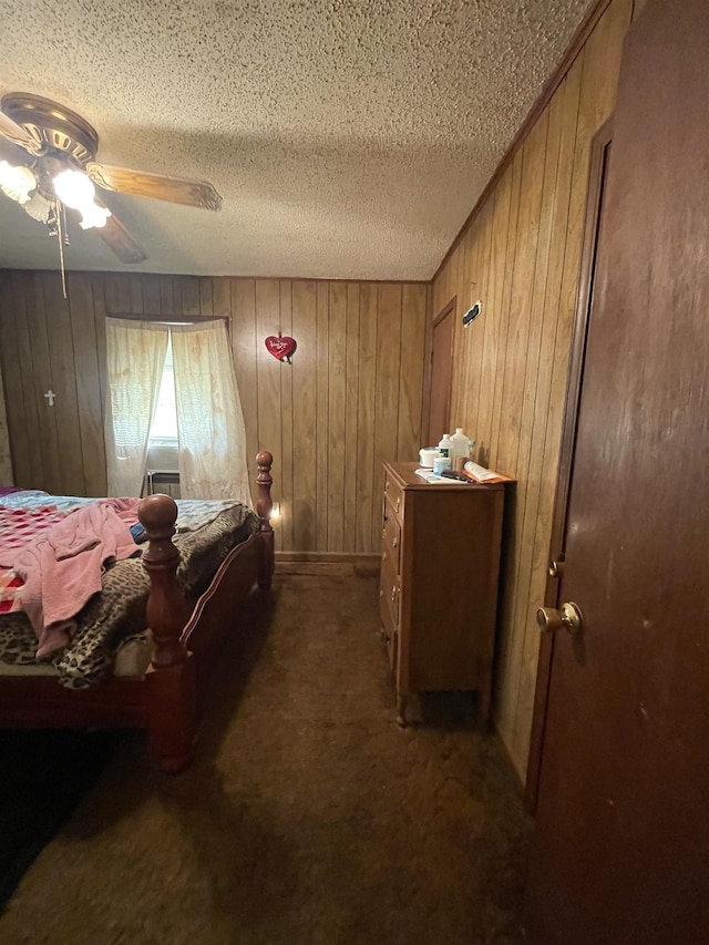 carpeted bedroom featuring ceiling fan, wood walls, and a textured ceiling