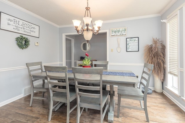 dining room featuring hardwood / wood-style flooring, crown molding, and a notable chandelier