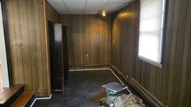 empty room featuring a paneled ceiling, wood walls, and stairs