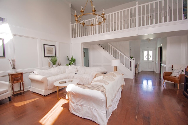 living room with a high ceiling, a chandelier, and dark hardwood / wood-style floors