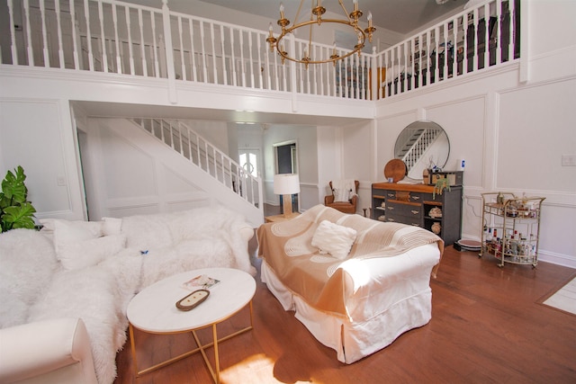 living room with a towering ceiling, dark hardwood / wood-style floors, and an inviting chandelier