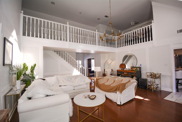 living room featuring dark wood-type flooring, a towering ceiling, and a chandelier