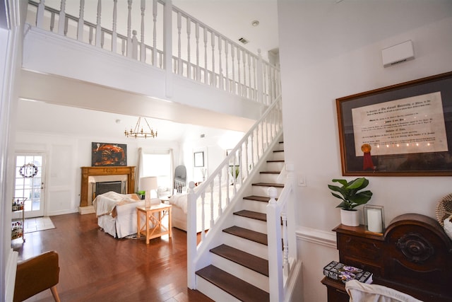 stairway featuring hardwood / wood-style flooring, a high ceiling, and a notable chandelier