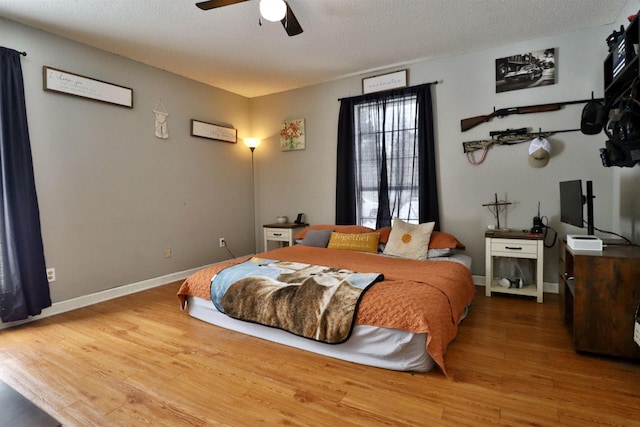 bedroom with ceiling fan, wood-type flooring, and a textured ceiling