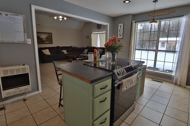 kitchen featuring hanging light fixtures, stainless steel electric stove, green cabinets, a kitchen island, and heating unit