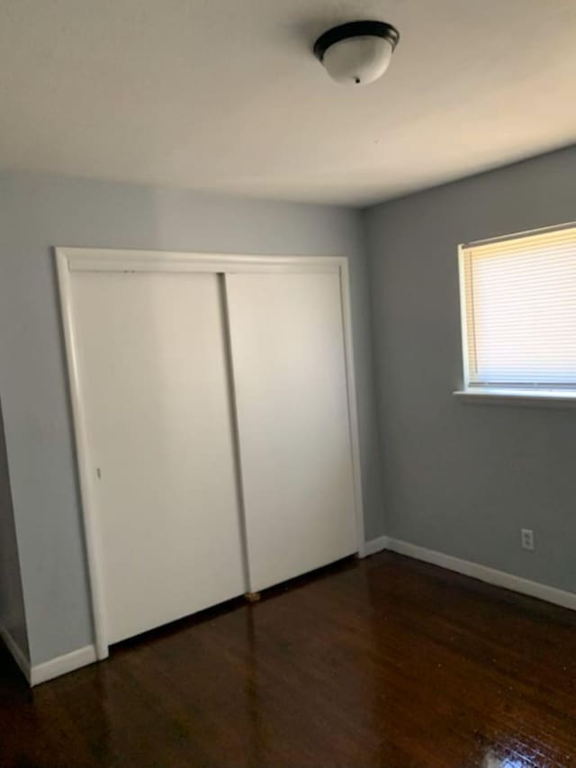 unfurnished bedroom with a closet and dark hardwood / wood-style flooring