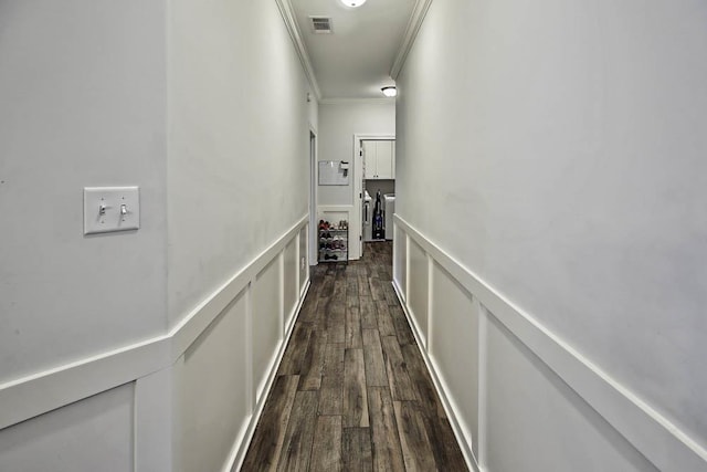 corridor with ornamental molding and dark wood-type flooring