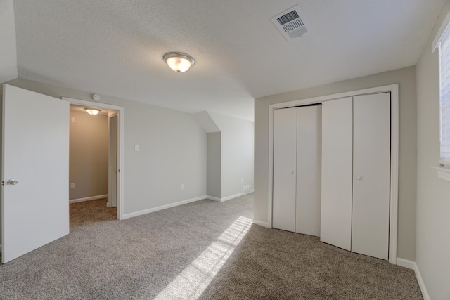 unfurnished bedroom featuring a closet, a textured ceiling, and light colored carpet