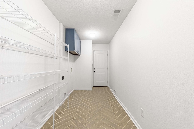 laundry room with visible vents, hookup for an electric dryer, baseboards, a textured ceiling, and cabinet space