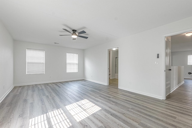 spare room with baseboards, a ceiling fan, and light wood finished floors