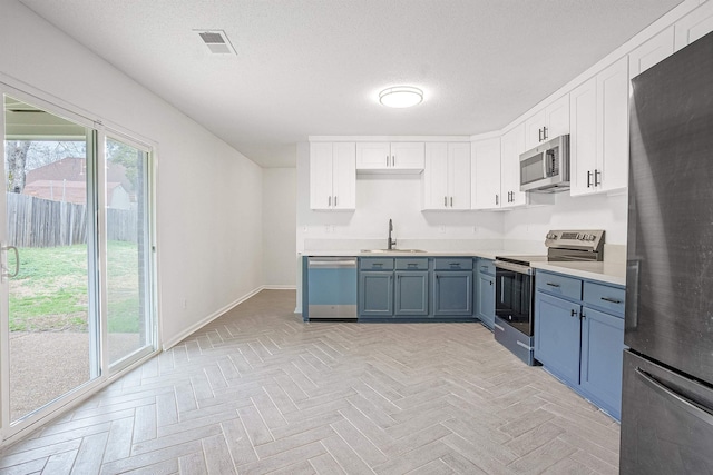 kitchen featuring a sink, visible vents, light countertops, white cabinetry, and stainless steel appliances