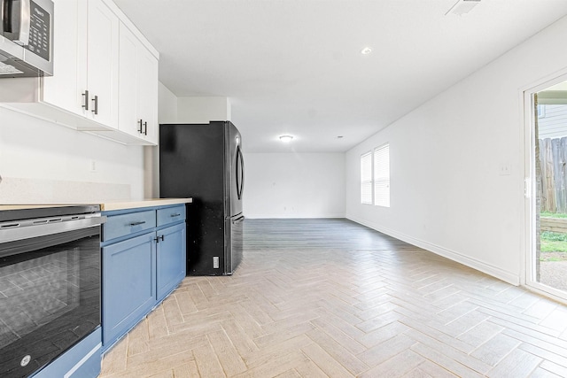 kitchen featuring baseboards, open floor plan, white cabinetry, light countertops, and stainless steel appliances