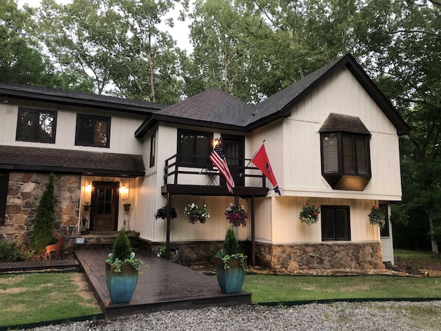 view of front of property featuring a balcony, stone siding, and roof with shingles