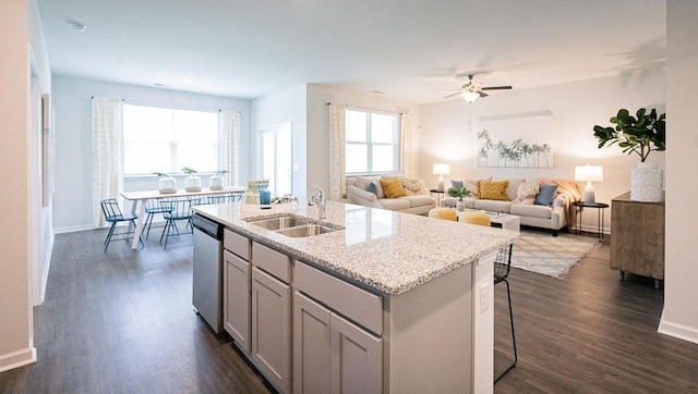 kitchen featuring a breakfast bar, a sink, open floor plan, stainless steel dishwasher, and a center island with sink