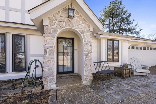 doorway to property with a garage and stone siding